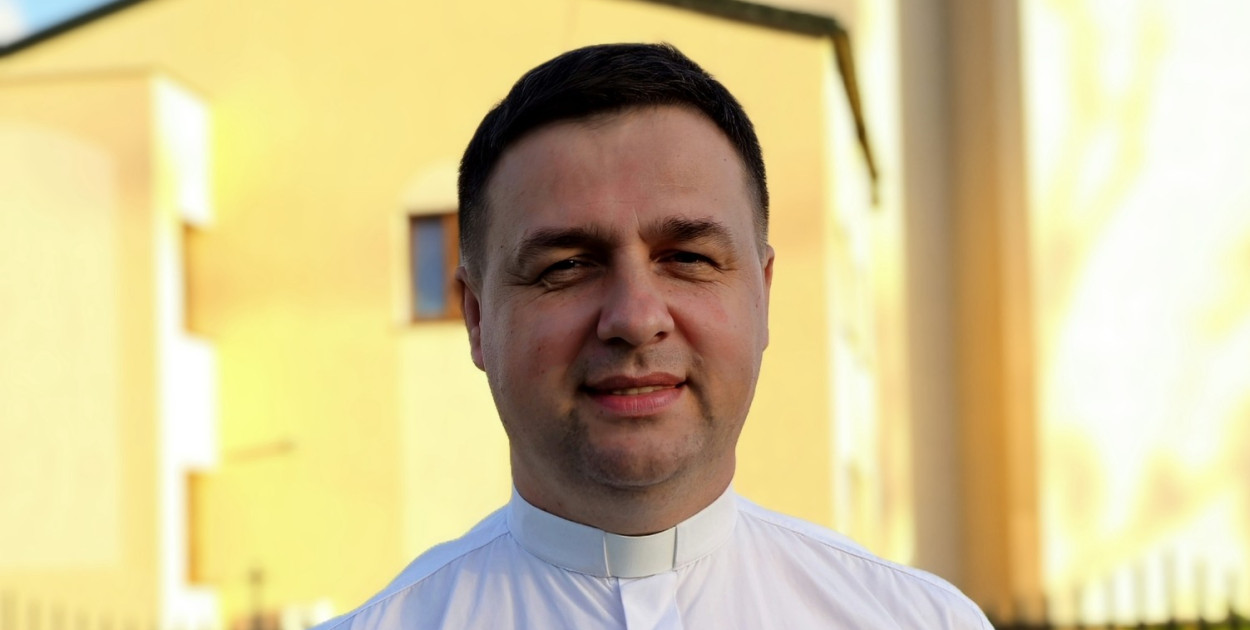 Na zdjęciu: ks. Krzysztof Ruciński przed świątynią parafialną. Fot. AI